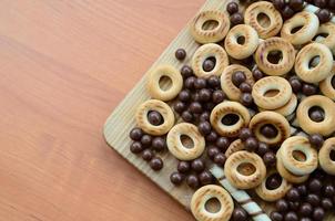 túbulos crujientes, bolas de chocolate y bagels yacen sobre una superficie de madera. mezcla de varios dulces foto