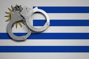 Uruguay flag and police handcuffs. The concept of crime and offenses in the country photo