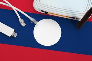 Laos flag depicted on table with internet rj45 cable, wireless usb wifi adapter and router. Internet connection concept photo