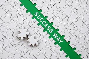 Success way. The green path is laid on the platform of a white folded jigsaw puzzle. The missing elements of the puzzle are stacked nearby photo