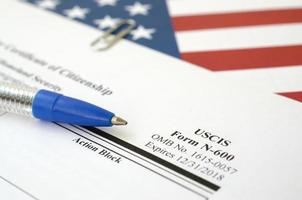 N-600 Application for Certificate of Citizenship blank form lies on United States flag with blue pen from Department of Homeland Security photo