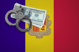 Andorra flag with handcuffs and a bundle of dollars. The concept of breaking the law and thieves crimes photo