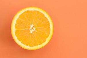 Top view of a one orange fruit slice on bright background in orange color. A saturated citrus texture image photo