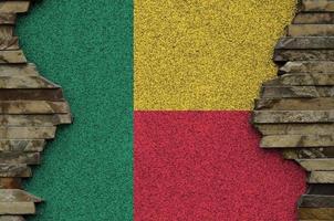 Benin flag depicted in paint colors on old stone wall closeup. Textured banner on rock wall background photo