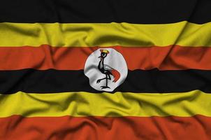 Uganda flag is depicted on a sports cloth fabric with many folds. Sport team banner photo