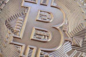 Close up shot of a physical bitcoin with a shiny relief surface made of chocolate. Abstract image of the crypto currency in an edible form photo