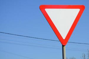 Traffic sign in the form of a white triangle. Give way photo