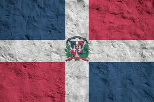 Dominican Republic flag depicted in bright paint colors on old relief plastering wall. Textured banner on rough background photo