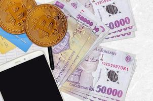 50000 Romanian leu bills and golden bitcoins with smartphone and credit cards. Cryptocurrency investment concept. Crypto mining or trading photo