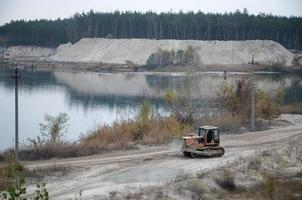 Quarry aggregate with heavy duty machinery. Caterpillar loader Excavator with backhoe driving to construction site quarry photo