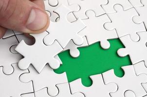 The human hand fills the last missing elements of the surface from the jigsaw puzzle. The concept of the completion of the initiated cases photo
