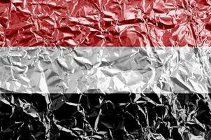 Yemen flag depicted in paint colors on shiny crumpled aluminium foil closeup. Textured banner on rough background photo