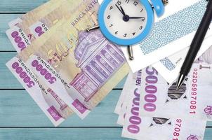 50000 Romanian leu bills and alarm clock with pen and envelopes. Tax season concept, payment deadline for credit or loan. Financial operations using postal service photo