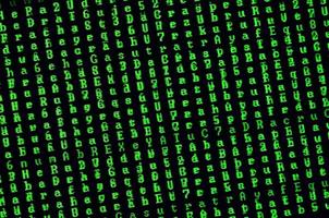 Macro shot of a glitch on the monitor of an office computer. The concept of introducing a virus into a personal data keeper. Stream of random green symbols on a black background photo