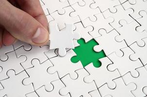 The human hand fills the last missing elements of the surface from the jigsaw puzzle. The concept of the completion of the initiated cases photo
