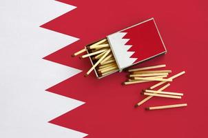 Bahrain flag is shown on an open matchbox, from which several matches fall and lies on a large flag photo