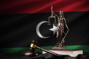 Libya flag with statue of lady justice, constitution and judge hammer on black drapery. Concept of judgement and guilt photo