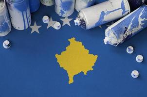 Kosovo flag and few used aerosol spray cans for graffiti painting. Street art culture concept photo