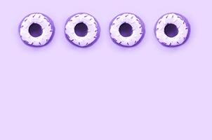 Many small plastic donuts lies on a pastel colorful background. Flat lay minimal pattern. Top view photo