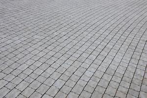 Gray color paving slabs in the pedestrian street sidewalk. Rough cobblestone pattern with many square shaped stones photo