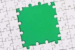 Framing in the form of a rectangle, made of a white jigsaw puzzle around the green space photo