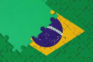 Brazil flag is depicted on a completed jigsaw puzzle with free green copy space on the left side photo