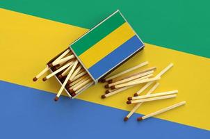 Gabon flag is shown on an open matchbox, from which several matches fall and lies on a large flag photo