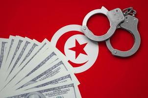 Tunisia flag with handcuffs and a bundle of dollars. The concept of illegal banking operations in US currency photo