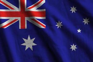 Australia flag with big folds waving close up under the studio light indoors. The official symbols and colors in banner photo