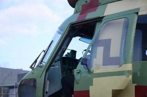 Helicopter cabin fragment close up. Camouflage aircraft fuselage and bulletproof glass photo