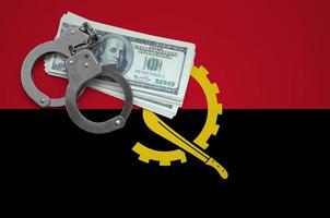 Angola flag with handcuffs and a bundle of dollars. The concept of breaking the law and thieves crimes photo