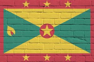 Grenada flag depicted in paint colors on old brick wall. Textured banner on big brick wall masonry background photo
