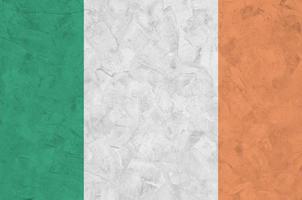 Ireland flag depicted in bright paint colors on old relief plastering wall. Textured banner on rough background photo