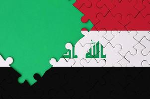 Iraq flag is depicted on a completed jigsaw puzzle with free green copy space on the left side photo