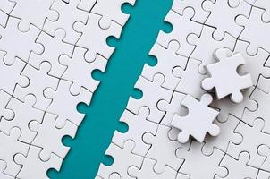 The blue path is laid on the platform of a white folded jigsaw puzzle. The missing elements of the puzzle are stacked nearby. Texture image with space for text photo