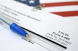 I-485 Application to register permanent residence or adjust status blank form lies on United States flag with blue pen from Department of Homeland Security photo