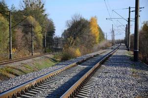 paisaje industrial de otoño. ferrocarril retrocediendo en la distancia entre árboles de otoño verdes y amarillos foto