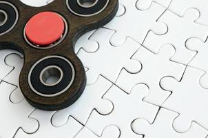 A wooden spinner lies on a white jigsaw puzzle background photo