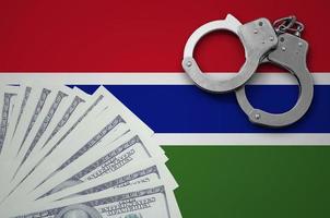 Gambia flag with handcuffs and a bundle of dollars. The concept of illegal banking operations in US currency photo