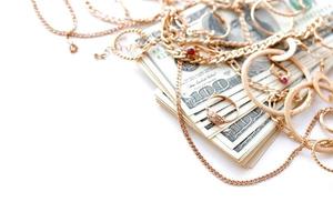 Many expensive golden jewerly rings, earrings and necklaces with big amount of US dollar bills on white background. Pawnshop or jewerly shop photo