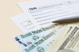 1040 Individual Income tax return form with Refund Check and hundred dollar bills on beige background photo