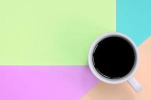 Small white coffee cup on texture background of fashion pastel pink, blue, coral and lime colors paper photo