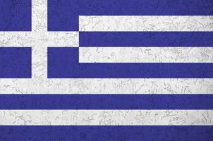 Greece flag depicted in bright paint colors on old relief plastering wall. Textured banner on rough background photo