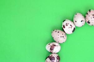 Quail eggs on a light green surface, top view, empty place for t photo