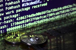 The digital process of cryptocurrency mining by using the GPUs. Bitcoins and video card on a working display and mining screen photo
