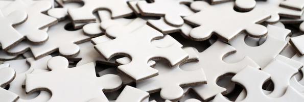Close-up of a pile of uncompleted elements of a white puzzle. A huge number of rectangular pieces from one large white mosaic photo