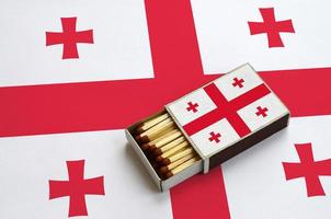 Georgia flag is shown in an open matchbox, which is filled with matches and lies on a large flag photo