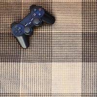 Video game controller lies on a checkered plaid photo