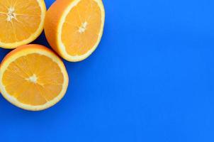 Top view of a several orange fruit slices on bright background in blue color. A saturated citrus texture image photo