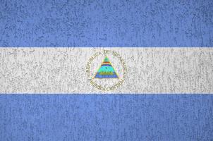 Nicaragua flag depicted in bright paint colors on old relief plastering wall. Textured banner on rough background photo